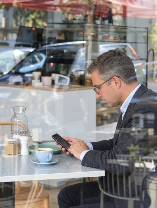 Homem de 40 anos pagando uma conta pelo celular num café